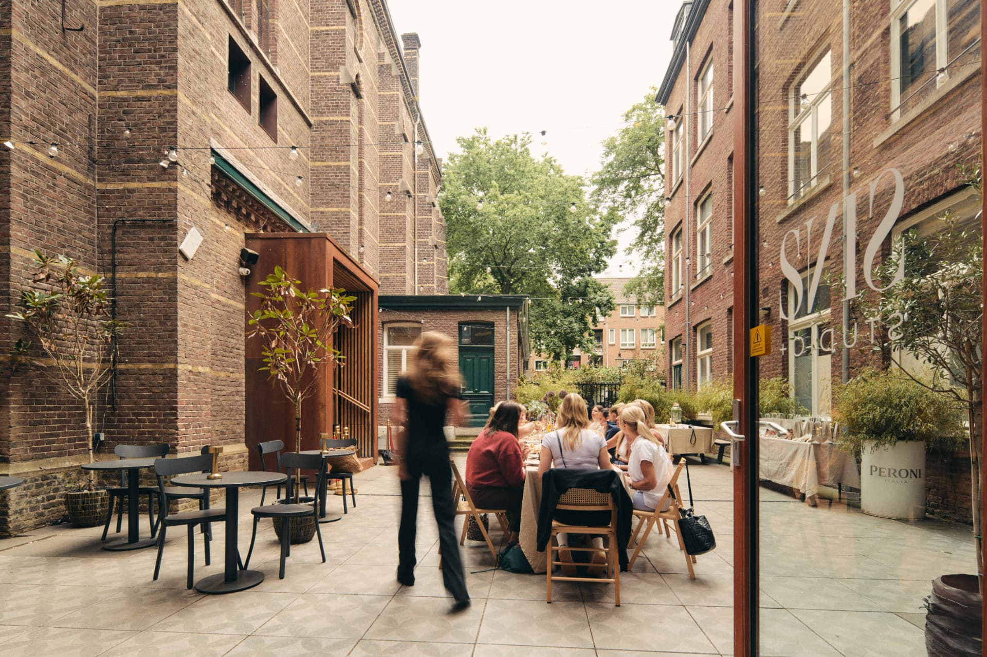 Binnenplaats van Sins Studio in Maastricht met gasten aan een lange tafel